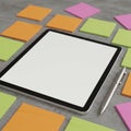 A tablet with a blank screen lies on a gray surface, surrounded by colorful sticky notes in Royalty Free Stock Photo