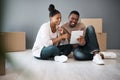 Tablet, box and moving with black couple in new house for planning, real estate and property. Investment, goals and Royalty Free Stock Photo