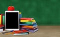 Tablet, colorful books, school supplies and apple on the table o Royalty Free Stock Photo