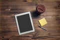 Tablet computer, coffee cup, pen and sticky paper on wood table