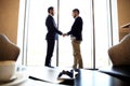 Tablet computer, coffee and smartphone with businessmen handshaking on background Royalty Free Stock Photo