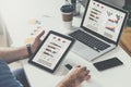 Tablet computer with graphs,diagrams and charts on screen in hands of young bearded businessman sitting at table