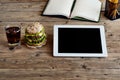 Tablet computer with a hamburger and a glass of cola