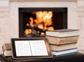 Tablet computer and pile books on the background of the fireplace