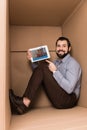 Cheerful handsome man pointing at tablet with couchsurfing website while sitting Royalty Free Stock Photo