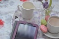 tablet with cup of coffe on tray and spring flowers on pink bedding. Relaxing, or working, or writing diary or blog in