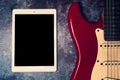 Tablet and electric guitar on grunge background Royalty Free Stock Photo