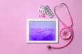 Tablet, flower, stethoscope and pills on pink background. Gynecological care