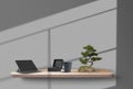 Tablet, gift box, cup and bonsai tree on a wooden shelf, suspended from the gray wall, shadows from the window on it