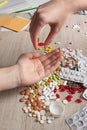 Tablet in girls hand over a table with other pills. Medical blisters and different pills Royalty Free Stock Photo