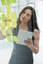 Tablet, glass wall and business woman writing, planning and strategy in office workplace. Sticky notes, brainstorming Royalty Free Stock Photo