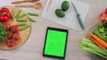 Tablet with green screen in the kitchen on table with fresh vegetables and fruit. Application for cooking. Healthy food Royalty Free Stock Photo