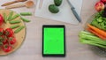 Tablet with green screen in the kitchen on table with fresh vegetables and fruit. Application for cooking. Healthy food Royalty Free Stock Photo