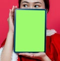 Tablet With Green Screen For Mockup Featuring an Asian Woman With Christmas Attire Presenting it While Covering Her Face Royalty Free Stock Photo