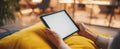 The tablet held in hands on a bright yellow cushion in a cozy environment..AI generated image Royalty Free Stock Photo