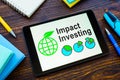 Tablet with Impact investing info and notebooks. Royalty Free Stock Photo