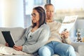 Tablet, newspaper and couple relax on sofa, bonding and streaming video at home. Technology, love and mature man reading Royalty Free Stock Photo