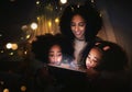 Tablet, night a mother reading to her kids in a tent while camping in the bedroom of their home together. Black family Royalty Free Stock Photo