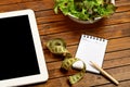 Tablet with notepad and vegetable salad Royalty Free Stock Photo