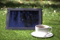 Tablet pc and a cup of coffee on the grass Royalty Free Stock Photo