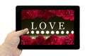 Tablet PC in hand with frame with love card with bush of red rose flowers and play of light on defocusing blur led lamps Royalty Free Stock Photo