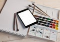 Tablet PC with watercolor paints and brushes on wooden table. Royalty Free Stock Photo