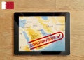 A Tablet PC which is displayed with map of Bahrain and Coronavirus text on the wooden table. Royalty Free Stock Photo
