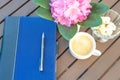 A tablet with a pen and in a vase white chocolate and an alpine rose on a wooden table and a cup of coffee with sweets Royalty Free Stock Photo