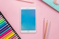 A tablet is on a pink background with a box of colored pencils Royalty Free Stock Photo