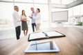 Tablet and planner in front of talking business people