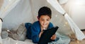 Tablet, relax and boy child in a tent playing an online game on the internet in the living room. Happy, entertainment Royalty Free Stock Photo