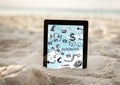 Tablet in sand showing black business doodles and sky