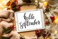 The tablet says the word hello September with red leaves and a dais on the wooden background. Concept of the autumn. Royalty Free Stock Photo