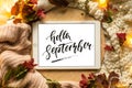 The tablet says the word hello September with red leaves and a dais on the wooden background. Concept of the autumn. Royalty Free Stock Photo