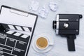 Tablet with a sheet of paper and a clapperboard lying on the table next to a retro video camera and a cup of coffee Royalty Free Stock Photo