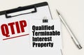 On the tablet, a sheet of paper and stickers with the inscription - QTIP, Qualified Terminable Interest Property Royalty Free Stock Photo