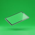 A tablet with a sleek, thin design and a glowing green screen floats against a matchin Royalty Free Stock Photo