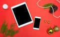 Tablet smart phone display on table on red screen for mockup in Christmas time. Christmas tree, decorations in background. Royalty Free Stock Photo