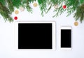 Tablet smart phone display on table on white screen for mockup in Christmas time. Christmas tree, decorations Royalty Free Stock Photo