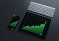 Tablet and smartphone displaying a digital line graph with an upward trend in green on a dark Royalty Free Stock Photo