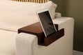 Tablet on sofa armrest wooden table in room. Interior element