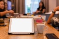 Tablet on table and coffee mug on table with group of friends on dinner table. Royalty Free Stock Photo