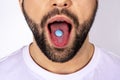 Pill on the tongue close-up. Man holding a blue pill in his mouth. Drug addiction and placebo effect