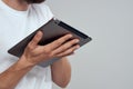 Tablet with a touch screen on a light background male hands white t-shirt cropped view Royalty Free Stock Photo