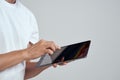 Tablet with a touch screen on a light background male hands white t-shirt cropped view Royalty Free Stock Photo