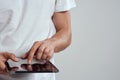 Tablet with a touch screen on a light background male hands white t-shirt cropped view Royalty Free Stock Photo