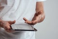Tablet with a touch screen on a light background male hands white t-shirt cropped view Royalty Free Stock Photo