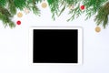 Tablet on white screen for mockup in Christmas time. Christmas tree, gifts, decorations on background. Royalty Free Stock Photo