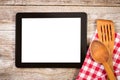 Tablet on wooden surface and serving spoons.