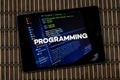 a tablet with the word programming over a writing code concept and a wooden background Royalty Free Stock Photo